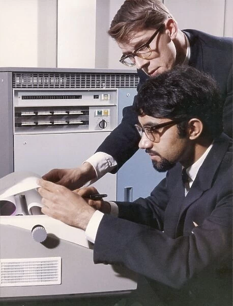 Programmers examining the printout from an old mainframe